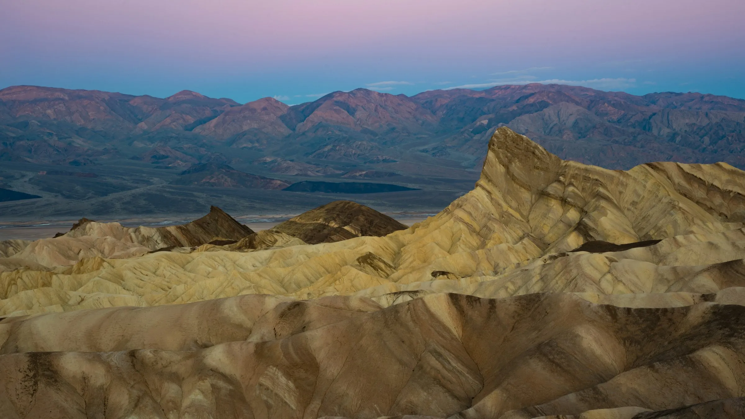 Zabriskie Point no Vale da Morte: colinas onduladas douradas e o pico Manly Beacon à luz suave do amanhecer