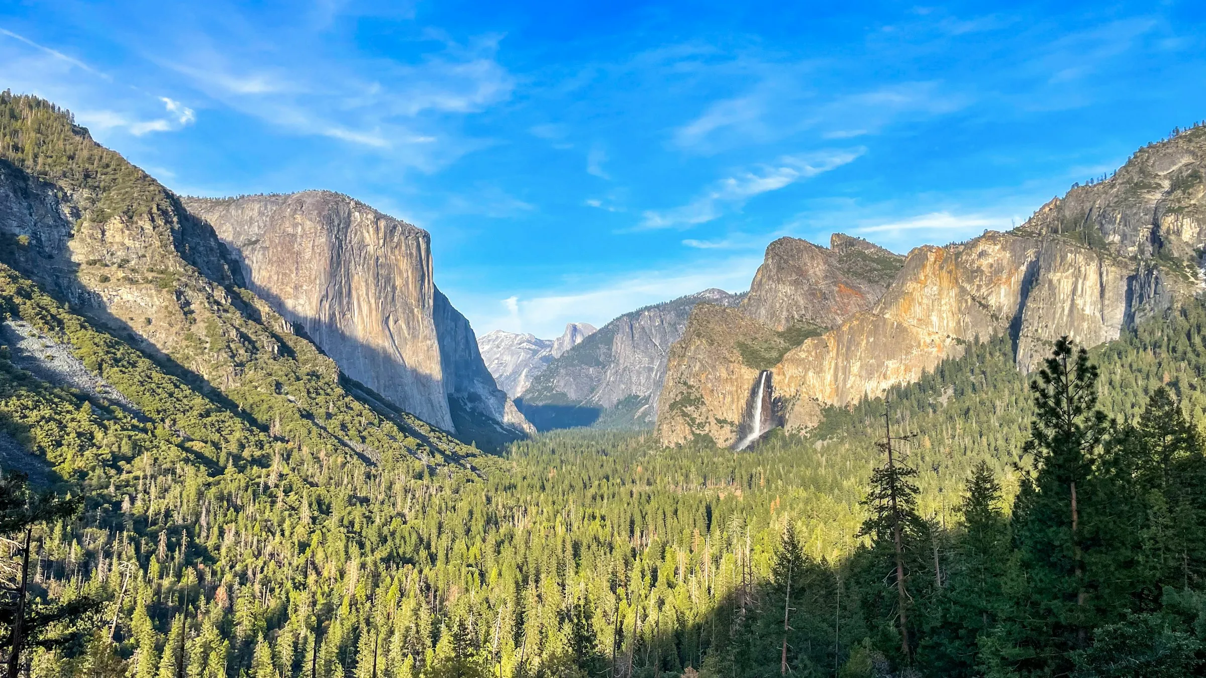 Tunnel View em Yosemite: o vale verde entre o El Capitán, à esquerda, e a cachoeira Bridalveil, à direita, sob céu azul