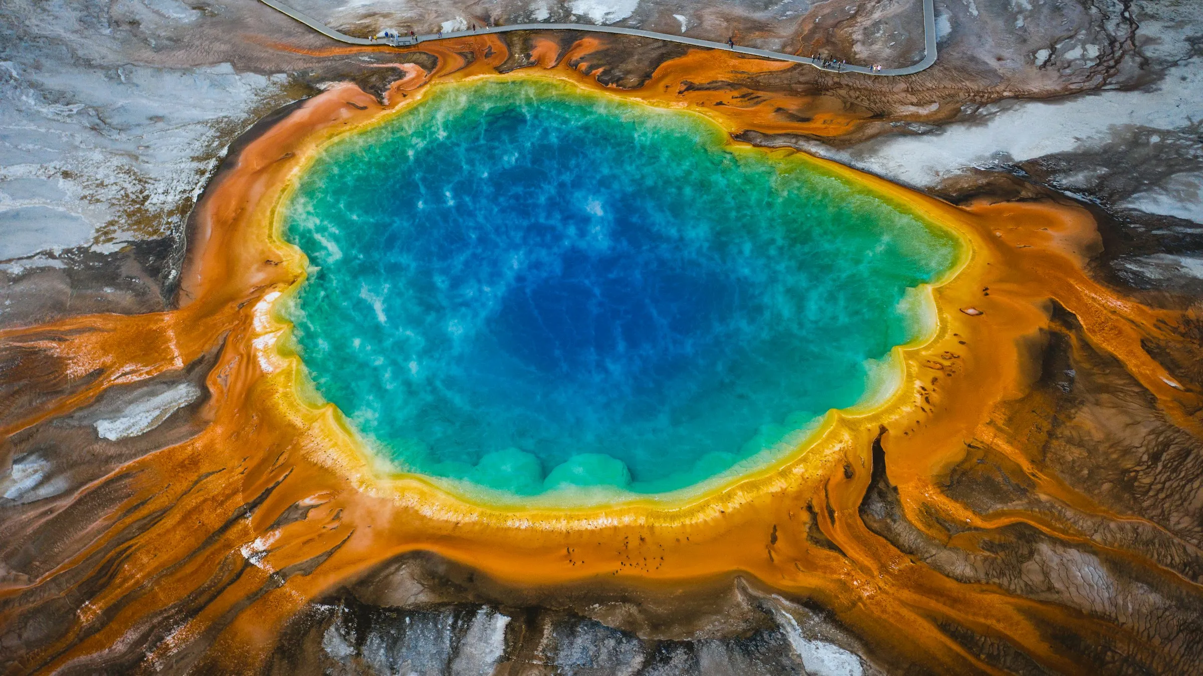 Grand Prismatic Spring vista do alto: fonte termal azul-turquesa cercada por faixas laranja e amarelas