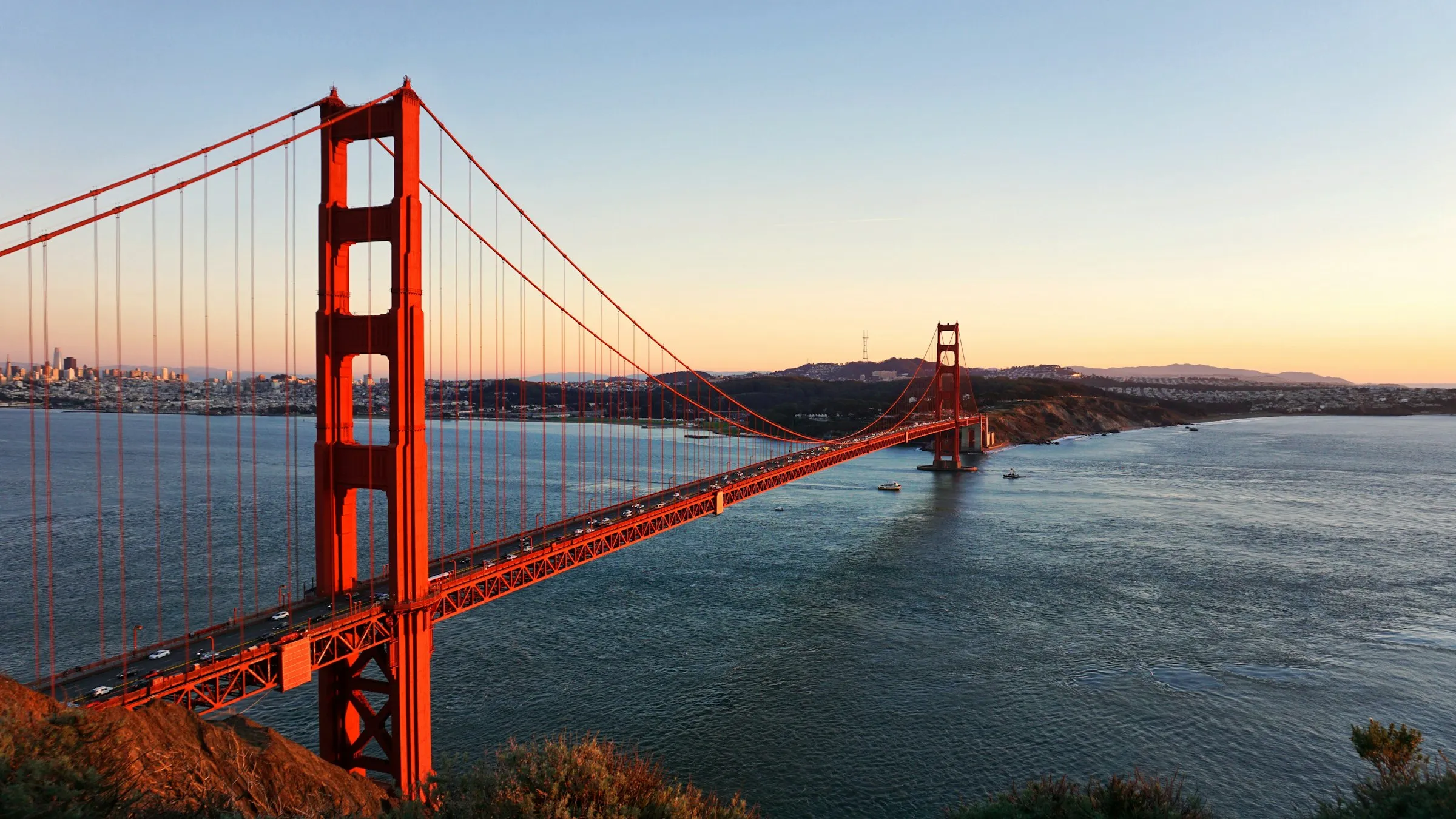 Ponte Golden Gate ao pôr do sol vista do alto da encosta, com a baía e San Francisco ao fundo